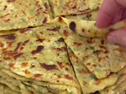 Stack of warm cheesy potato herb flatbreads, one torn open showing melted cheese