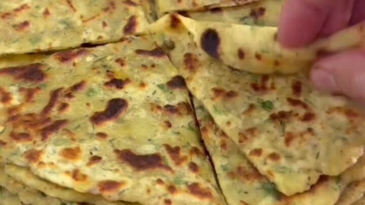 Stack of warm cheesy potato herb flatbreads, one torn open showing melted cheese