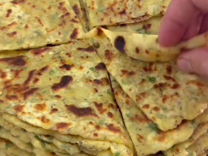 Stack of warm cheesy potato herb flatbreads, one torn open showing melted cheese