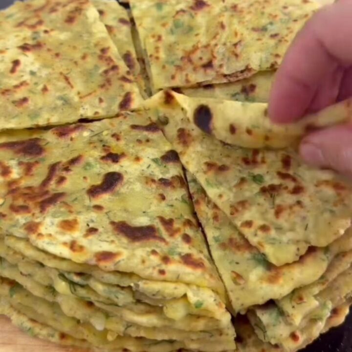 Stack of warm cheesy potato herb flatbreads, one torn open showing melted cheese