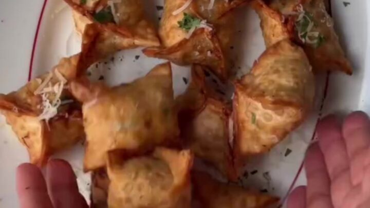 Crispy golden chicken rangoons with a creamy garlic Parmesan dip, one broken open showing the filling