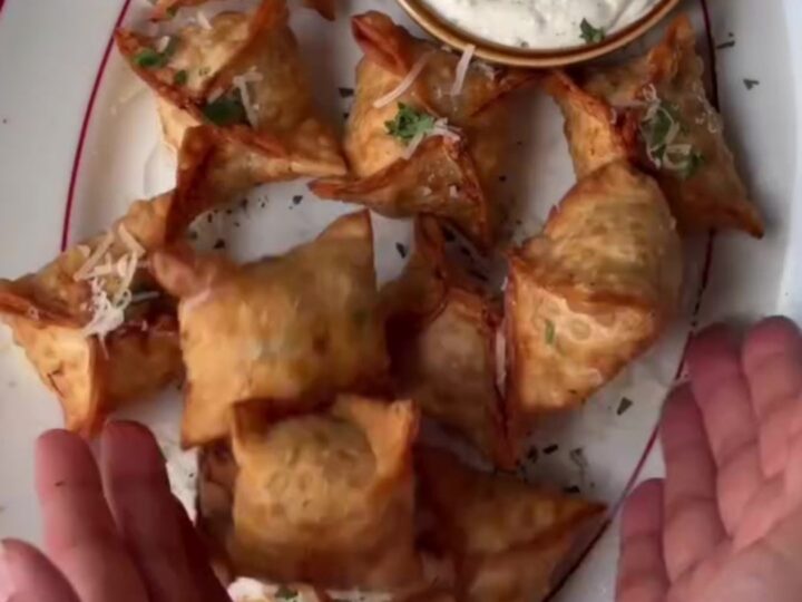 Crispy golden chicken rangoons with a creamy garlic Parmesan dip, one broken open showing the filling