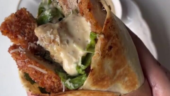 Crispy chicken Caesar wrap sliced diagonally, showing golden chicken, lettuce, and creamy sauce