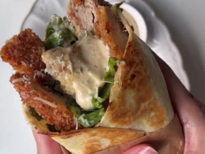 Crispy chicken Caesar wrap sliced diagonally, showing golden chicken, lettuce, and creamy sauce