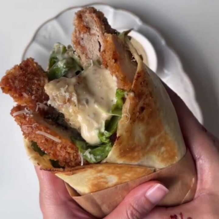 Crispy chicken Caesar wrap sliced diagonally, showing golden chicken, lettuce, and creamy sauce