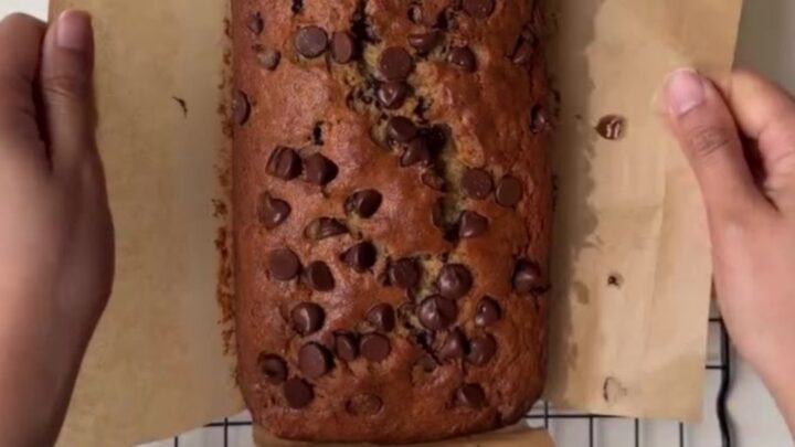 Sliced brown butter chocolate chip banana bread on a wooden board, showing moist crumb and melted chocolate
