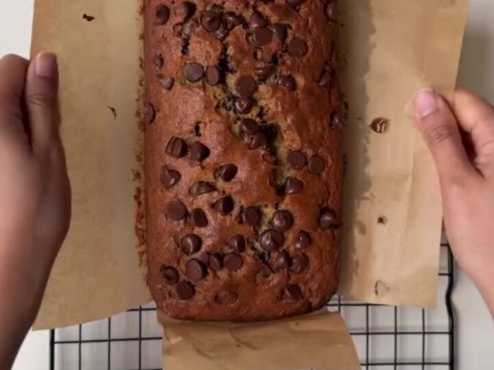Sliced brown butter chocolate chip banana bread on a wooden board, showing moist crumb and melted chocolate