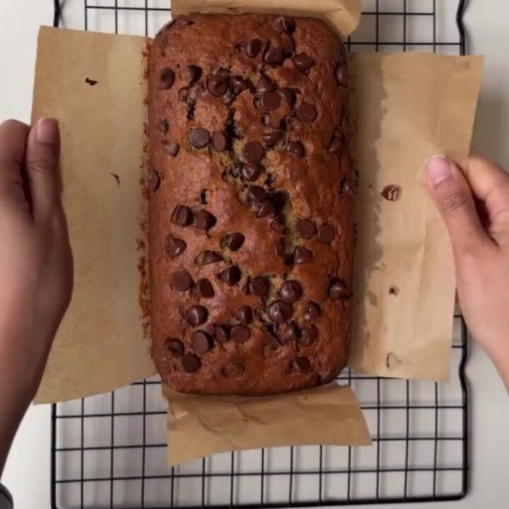 Sliced brown butter chocolate chip banana bread on a wooden board, showing moist crumb and melted chocolate