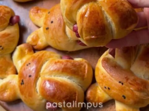Golden bunny-shaped buns brushed with butter, one pulled open showing soft crumb and sausage