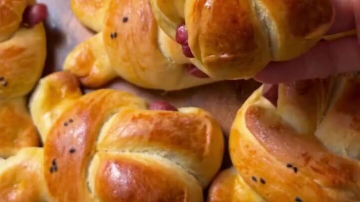 Golden bunny-shaped buns brushed with butter, one pulled open showing soft crumb and sausage