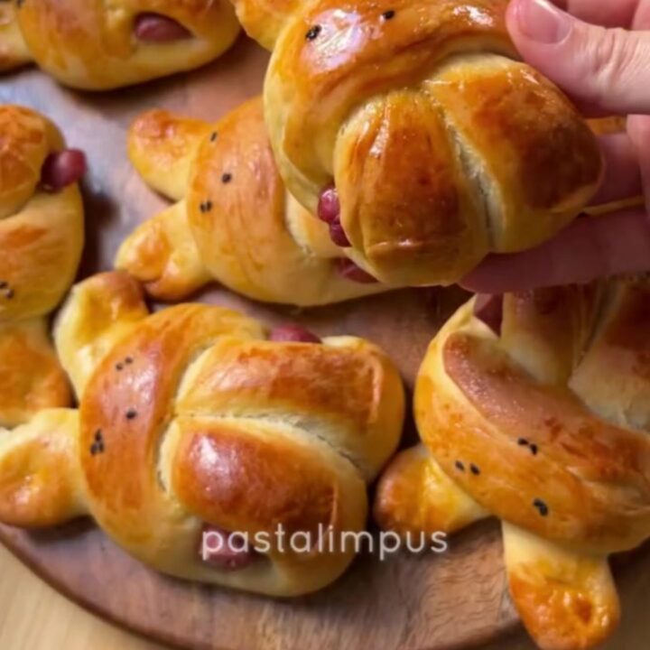 Golden bunny-shaped buns brushed with butter, one pulled open showing soft crumb and sausage