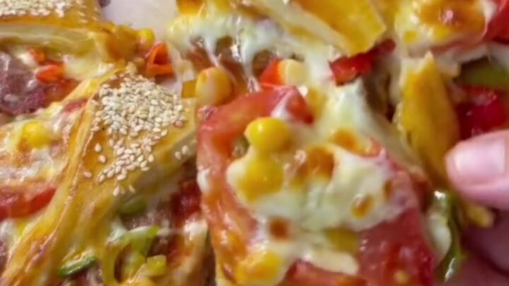 Golden crown pizza ring with bubbling mozzarella and sucuk, sesame-crusted, on parchment