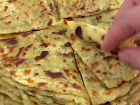 Golden brown lavaş flatbread brushed with melted butter, folded on a wooden board