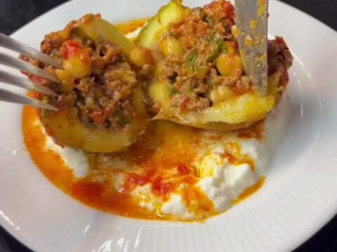 Stuffed round zucchini with beef and chickpeas, sliced open to show the filling in tomato gravy