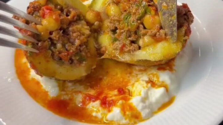 Stuffed round zucchini with beef and chickpeas, sliced open to show the filling in tomato gravy
