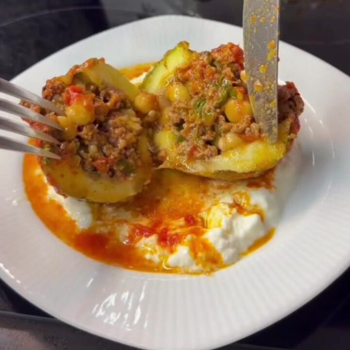 Stuffed round zucchini with beef and chickpeas, sliced open to show the filling in tomato gravy