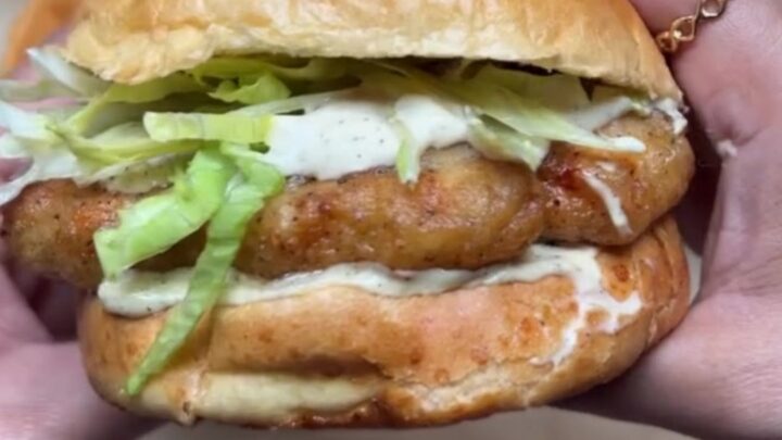 Crispy copycat McChicken sandwich on a brioche bun with lettuce and mayo sauce, taken a bite.