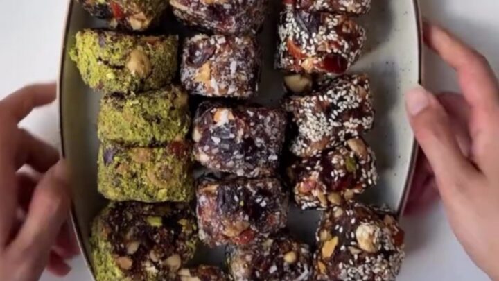 Sliced no-bake cardamom date nut rolls showing pistachio and walnut pieces in dark date caramel.