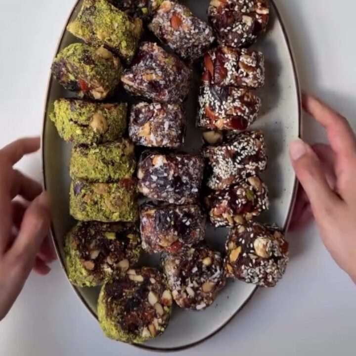 Sliced no-bake cardamom date nut rolls showing pistachio and walnut pieces in dark date caramel.