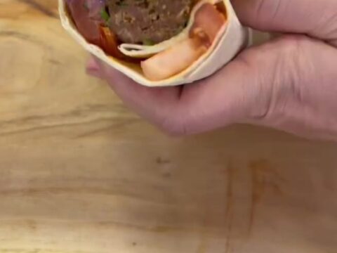 Crispy dürüm wrap sliced in half, showing juicy kebab and sumac onions