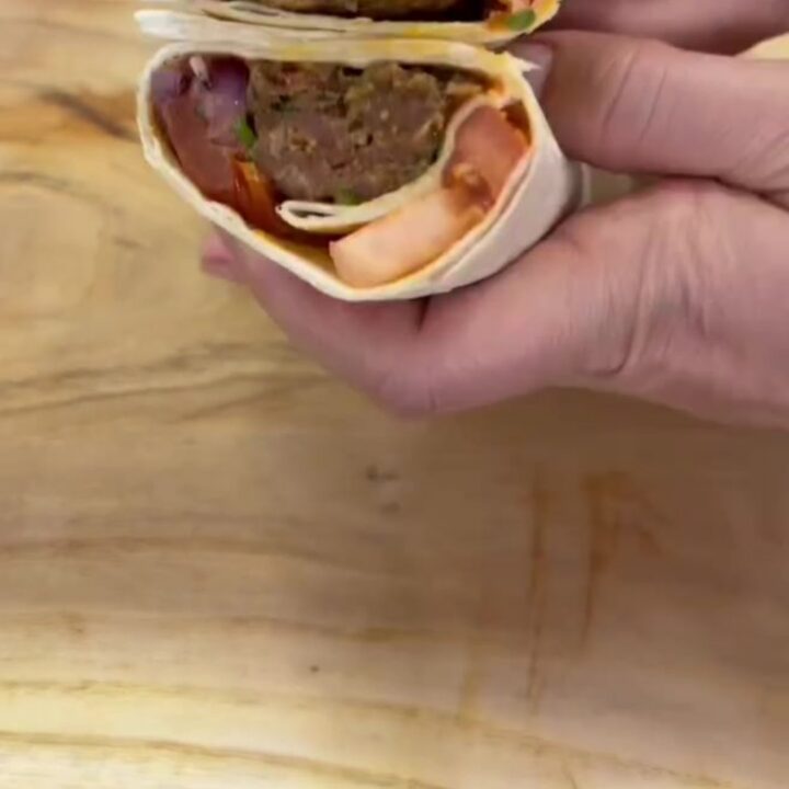 Crispy dürüm wrap sliced in half, showing juicy kebab and sumac onions