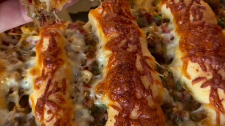 Golden pull-apart pide bread with seasoned ground beef and melted cheese, showing a slice being lifted with a spatula.