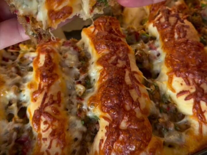 Golden pull-apart pide bread with seasoned ground beef and melted cheese, showing a slice being lifted with a spatula.