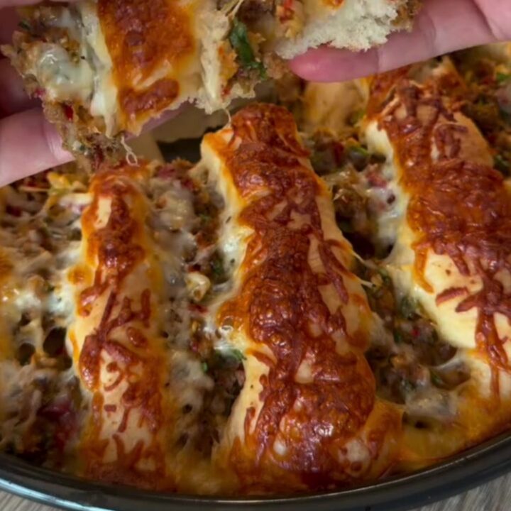 Golden pull-apart pide bread with seasoned ground beef and melted cheese, showing a slice being lifted with a spatula.