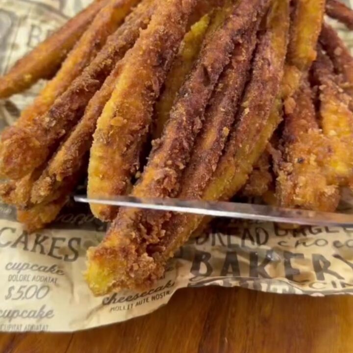 A crispy blooming eggplant fan fry on a plate, with golden brown petals and a small bowl of white yogurt dip with mint.