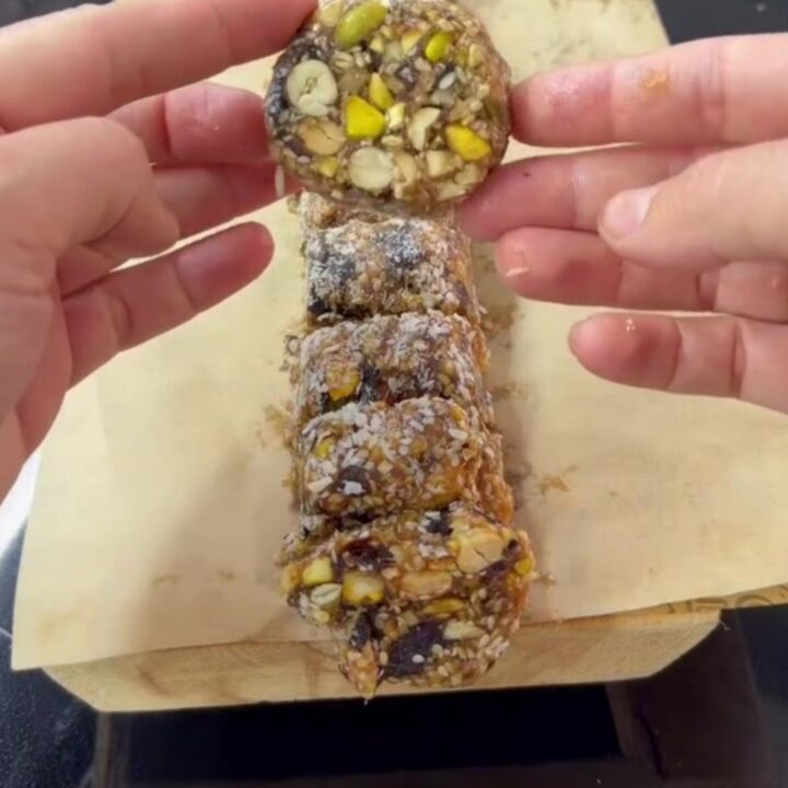 Sliced energy roll medallions showing pistachios and nuts in dark date fudge