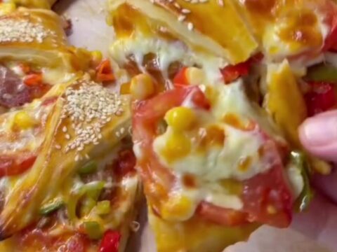 Golden ring pizza with melted cheese and sucuk, sliced to show cheese pull