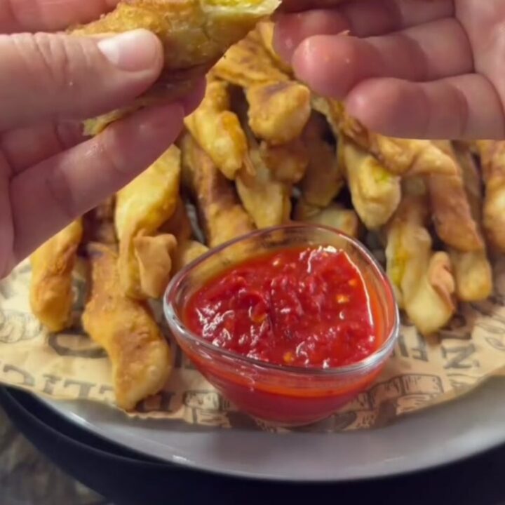 Twisted golden potato churro fries with sweet chili sauce, one fry dipped and showing a crispy shell and soft interior.