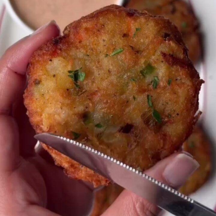 Crispy potato veggie patty being dipped into spicy Kewpie sauce, with melted cheddar visible