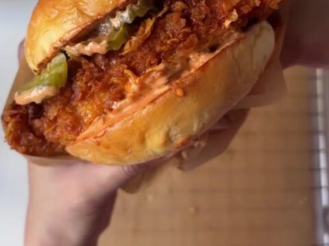 Crispy fried chicken sandwich with melted cheese, pickles, and lettuce on toasted bread