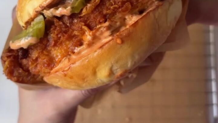 Crispy fried chicken sandwich with melted cheese, pickles, and lettuce on toasted bread