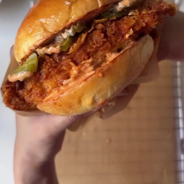 Crispy fried chicken sandwich with melted cheese, pickles, and lettuce on toasted bread