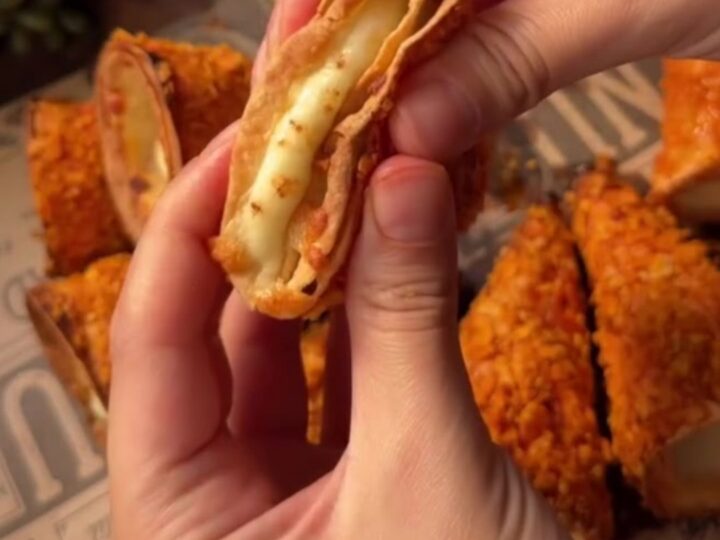 Pulling apart a crunchy nacho stuffed cone with a long stretch of molten cheese