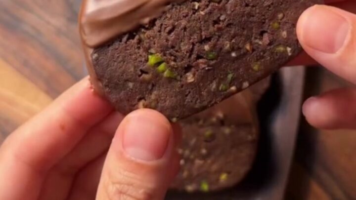 Chocolate-dipped banana biscuit discs with pistachios on parchment paper