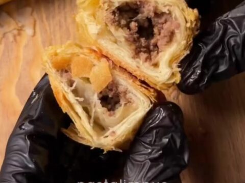 Golden brown börek triangles on a baking sheet, flaky layers visible