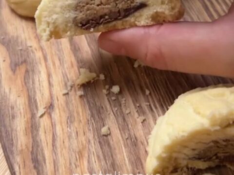 A shortbread cookie broken in half, showing a glossy molten hazelnut chocolate center oozing out