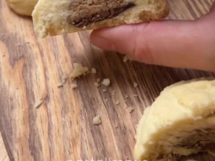 A shortbread cookie broken in half, showing a glossy molten hazelnut chocolate center oozing out