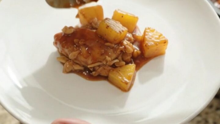 Shredded pineapple BBQ chicken in a slow cooker with glossy sauce and caramelized pineapple chunks