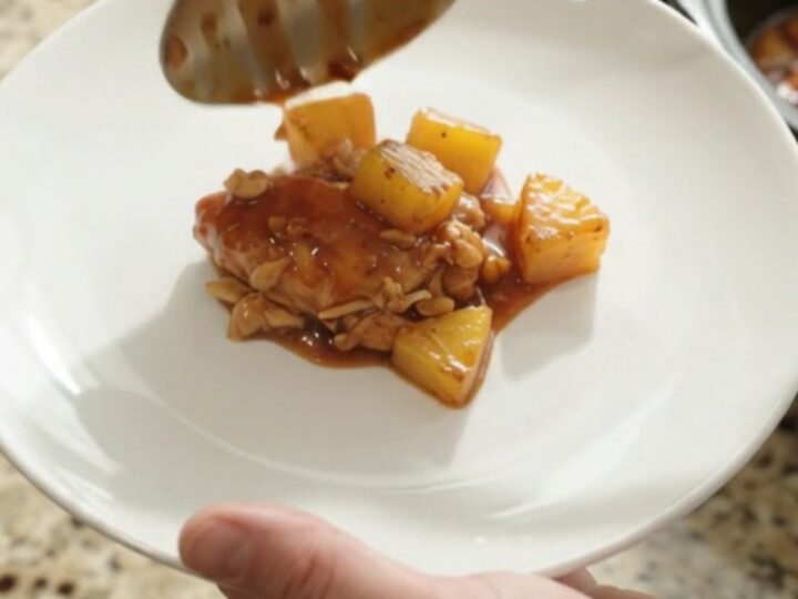 Shredded pineapple BBQ chicken in a slow cooker with glossy sauce and caramelized pineapple chunks