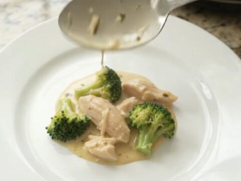 Creamy Crockpot chicken and broccoli with melted cheddar sauce, served in a white bowl