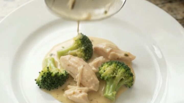 Creamy Crockpot chicken and broccoli with melted cheddar sauce, served in a white bowl