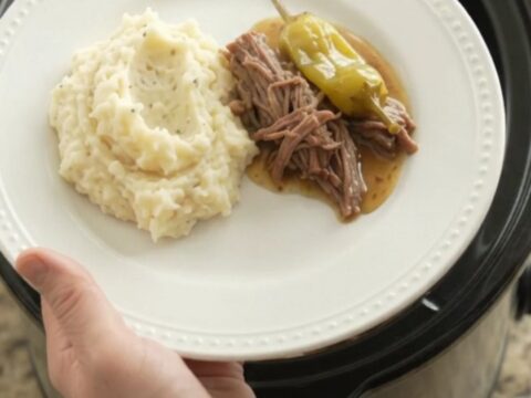 Mississippi pot roast in a slow cooker with shredded beef and pepperoncini in a golden gravy