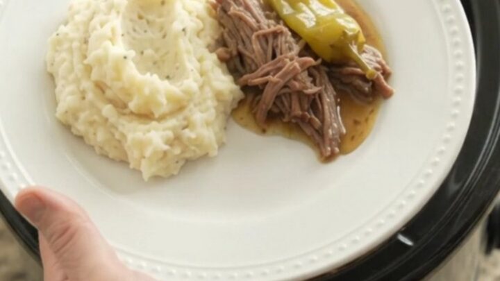 Mississippi pot roast in a slow cooker with shredded beef and pepperoncini in a golden gravy