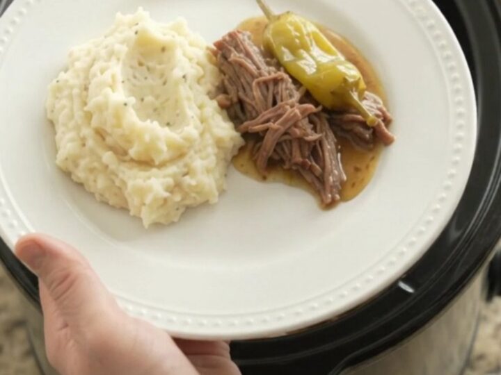 Mississippi pot roast in a slow cooker with shredded beef and pepperoncini in a golden gravy