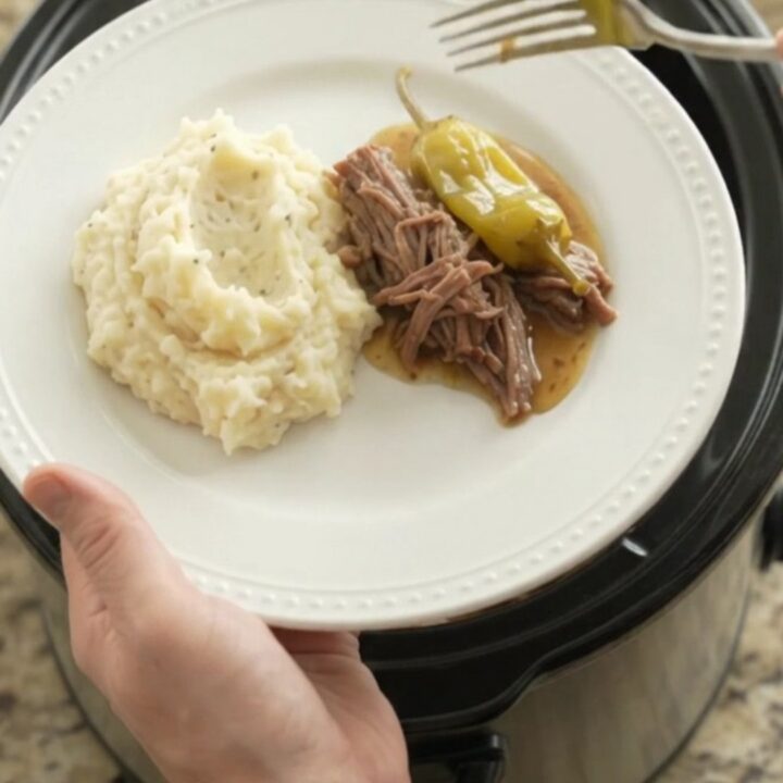 Mississippi pot roast in a slow cooker with shredded beef and pepperoncini in a golden gravy