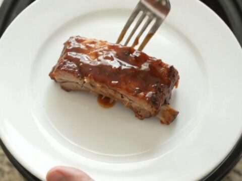 Slow-cooker BBQ ribs glistening with sticky sauce on a white plate.
